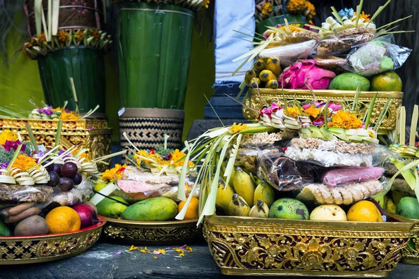 Traditionella erbjudanden till gudar i Indonesien med blommor, frukter och aromatiska pinnar i templet, buddhist — Stockfoto