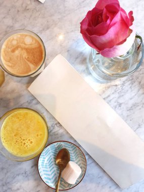 Boş bir menü ve bir kafede içecekler, kapuçino ve portakal suyu, şekerler ve pembe bir gül.