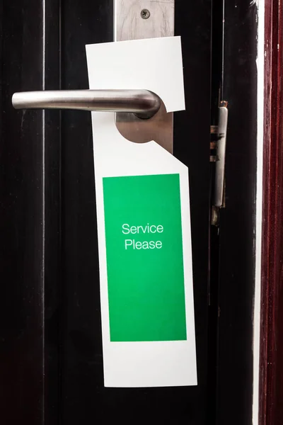 label on a door with writing service please in a hotel