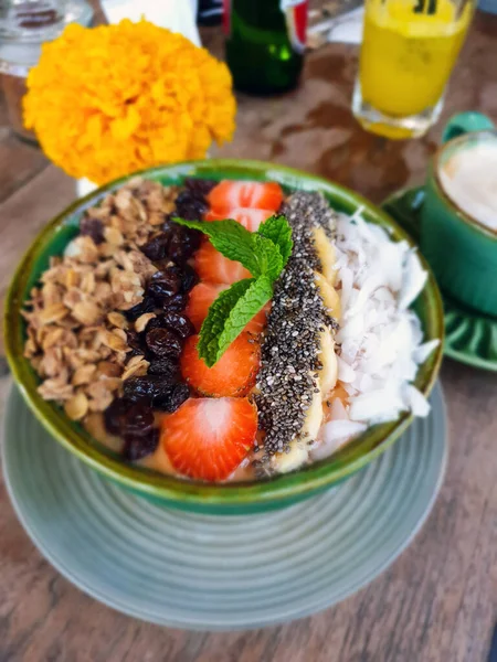 Organik müsli yoğurdu, üzerinde çilek, muz, chia tohumu ve hindistan cevizi var.