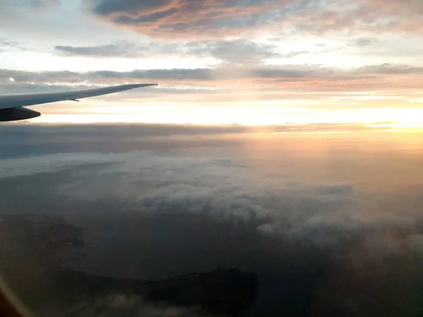 Uitzicht vanuit vliegtuig raam in de wolken met kleurrijke zonsopgang — Stockfoto