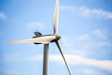 Modern yel değirmeni güneşli bir günde ve cennet gibi beyaz bulutlarla, ön planda yakın plan, Enerji kavramı