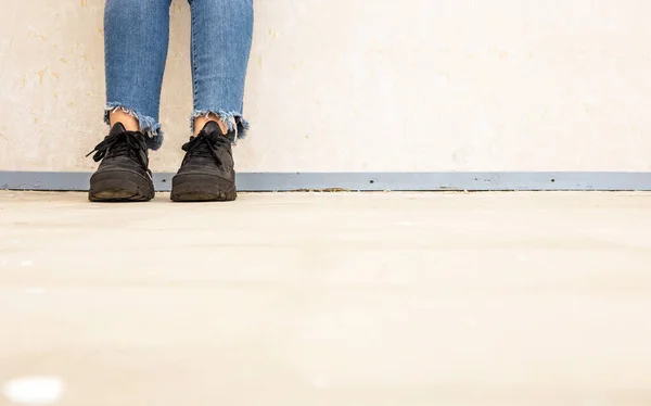 Woman with leather white sneaker wearing blue jeans and sports shoe walking near white wall Fashion concept