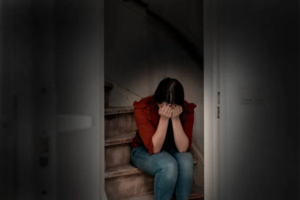 Jonge vrouw huilt en zit op een trap in het donker, eenzaam verdrietig en depressief meisje houdt haar hoofd naar beneden — Stockfoto