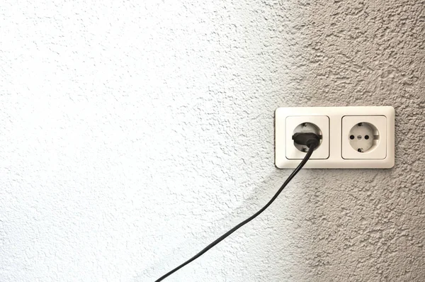 Siyah kabloyla çift elektrik prizi ve metin için beyaz duvar boşluğu