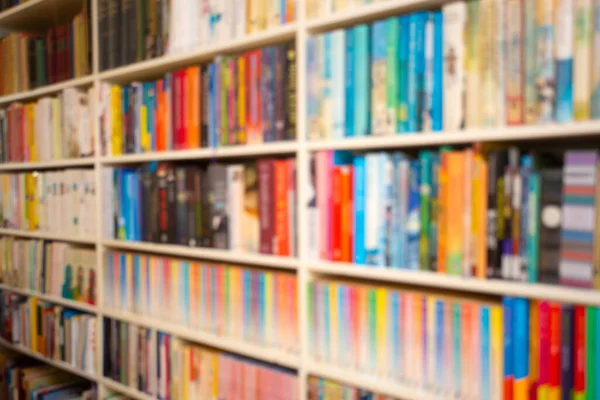 Police s knihami různé barvy v obývacím pokoji nebo knihovně rozmazané pozadí retro design — Stock fotografie