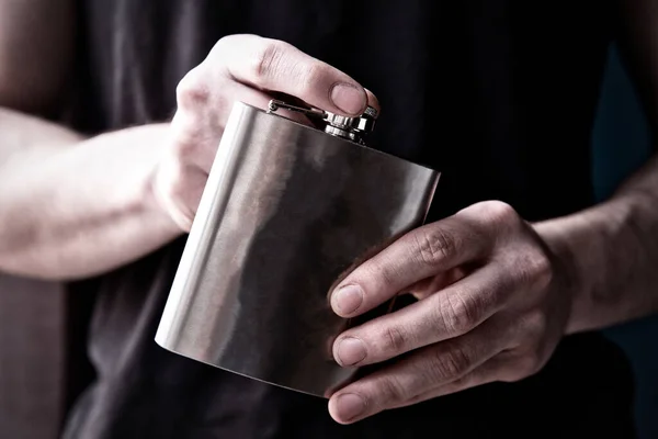 Young man holding a stainless steele Hip Flask with liquor, alcohol and booze concept Stock Picture