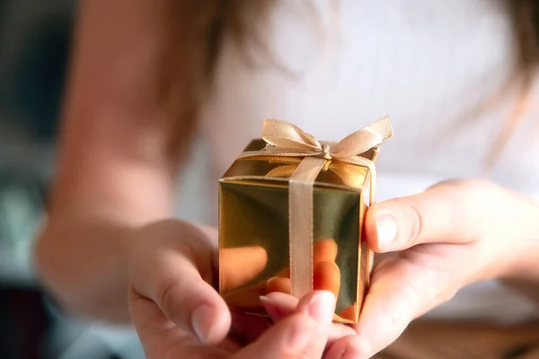 Жіночі руки, що тримають золоту коробку з подарунками, подарунок на свято, день народження, Різдво, батько або мати, Валентинів день близько — стокове фото