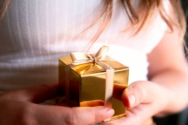Жіночі руки, що тримають золоту коробку з подарунками, подарунок на свято, день народження, Різдво, батько або мати, Валентинів день близько — стокове фото