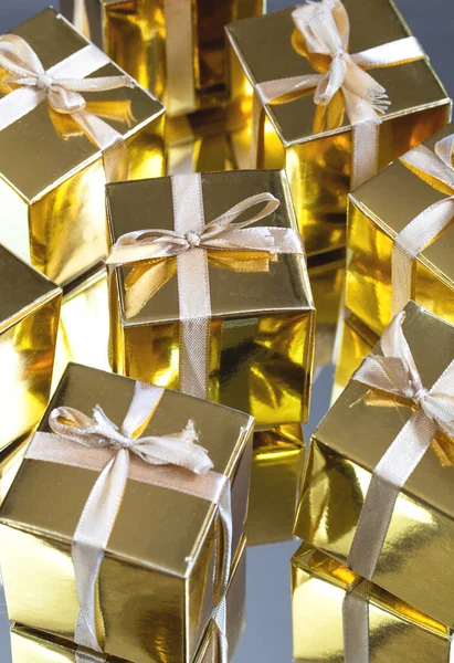 Group of gold sparkling gift boxes on grey background with reflection. A set of gold gift boxes for present, suprise,birthday,Christmas concept