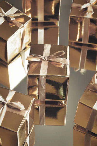 Группа золотых сверкающих подарочных коробок на сером фоне с отражением. Набор золотых подарочных коробок на подарок, сюрприз, день рождения, рождественская концепция — стоковое фото