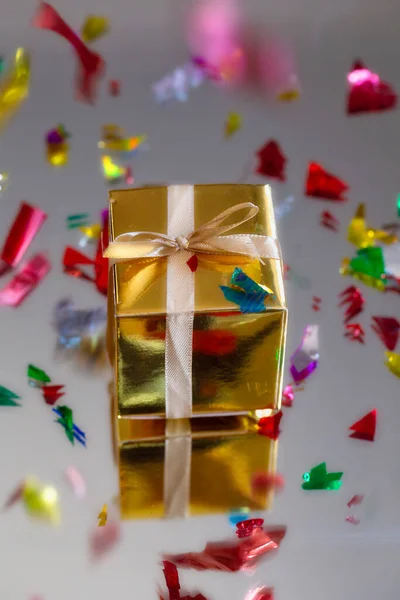 Группа золотых сверкающих подарочных коробок на сером фоне с отражением и конфетти. Набор золотых подарочных коробок на подарок, сюрприз, день рождения, рождественская концепция — стоковое фото