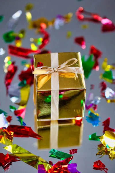 Группа золотых сверкающих подарочных коробок на сером фоне с отражением и конфетти. Набор золотых подарочных коробок на подарок, сюрприз, день рождения, рождественская концепция — стоковое фото