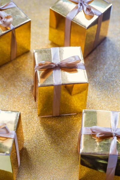 Group of gold sparkling gift boxes, beautiful gold packaging surprise with bow on sparkling background