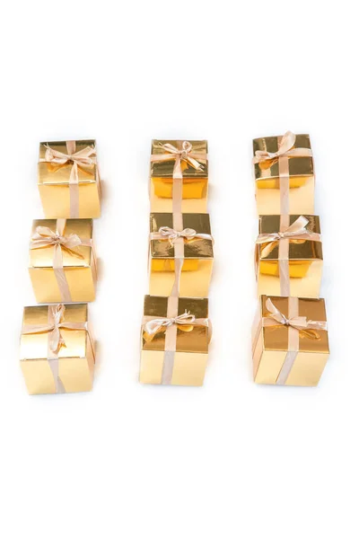 Gruppo di scatole regalo o regalo in oro scintillante di fila con fiocco isolato su sfondo bianco, — Foto Stock