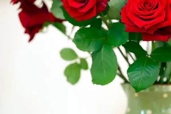 Strauß schöner roter Rosen in grüner Vase auf buntem Hintergrund in gemütlichem Zuhause, Valentinskonzept — Stockfoto