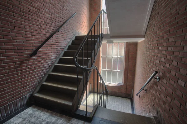 Escalera en edificio de apartamentos con pared de ladrillo, escalera antigua complejo de estilo antiguo con ventanas altas — Foto de Stock