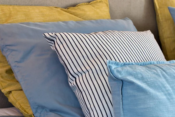 Primer plano de almohadas amarillas y azules claro en una fila en la cama, decoración retro moderna para el hogar, colores pastel luz colorido brillante — Foto de Stock