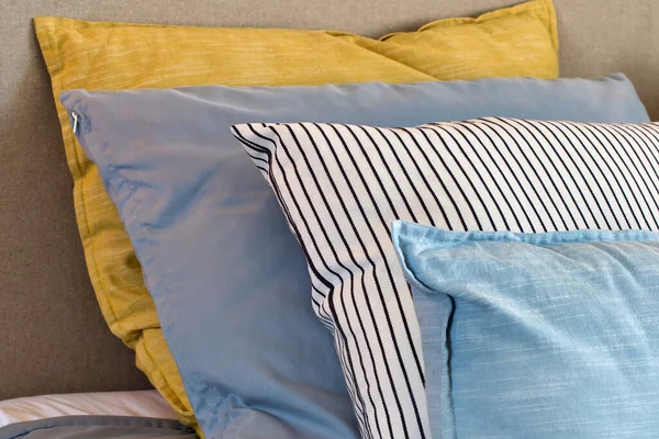 Zbliżenie żółtych i jasnoniebieskich poduszek w rzędzie na łóżku, nowoczesna dekoracja retro dla domu, pastelowe jasne kolory kolorowe jasne — Zdjęcie stockowe
