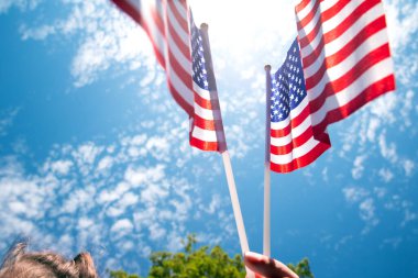 Mavi gökyüzünde Amerika Birleşik Devletleri için bayrak sallayan, yakın plan güzellikte iki Amerikan bayraklarıyla.