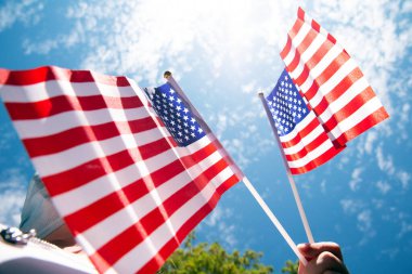 Mavi gökyüzünde Amerika Birleşik Devletleri için bayrak sallayan, yakın plan güzellikte iki Amerikan bayraklarıyla.