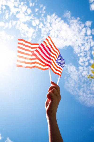 Χέρι Κρατώντας Δύο Αμερικανικές Σημαίες Στον Γαλάζιο Ουρανό Φόντο Φως — Φωτογραφία Αρχείου