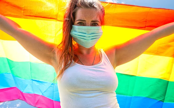 Jovem acenando com uma bandeira do arco-íris pelos direitos LGBT, liberdade para o conceito homossexual de Lgbtq, usando uma máscara de segurança para Covid-19, coronavírus. Protesto — Fotografia de Stock