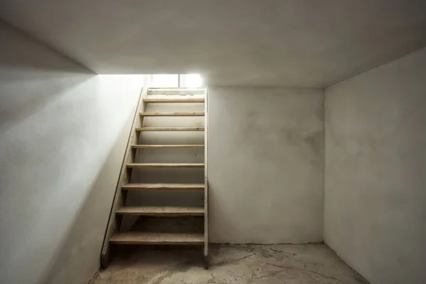 Sótano vacío en antiguo edificio industrial abandonado con poca luz y unas escaleras de madera — Foto de Stock