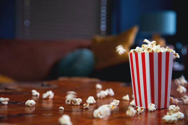 Popcorn terbang keluar dari kotak kardus. ember bergaris-garis merah dan putih dengan popcorn terbang di ruang tamu, film atau konsep bioskop — Stok Foto