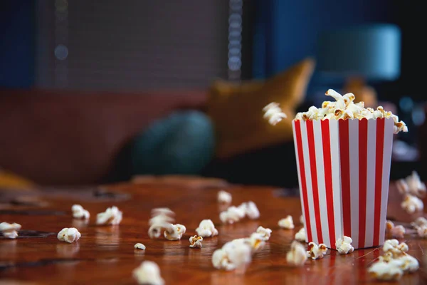 Palomitas de maíz volando de la caja de cartón. cubo de palomitas rayado rojo y blanco con palomitas voladoras en la sala de estar, película o concepto de cine — Foto de Stock