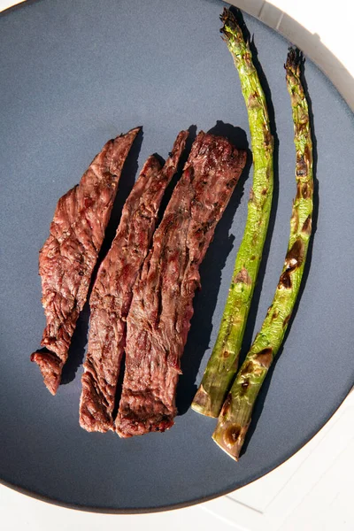 Grilled beef steak with Green asparagus on blue plate and white background top view, barbecue dry aged steak — Stock Photo, Image