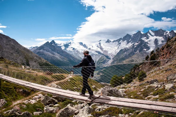 Один человек молодой человек, идущий по подвесному мосту в Швейцарии, путешествующий с красивым пейзажем — стоковое фото