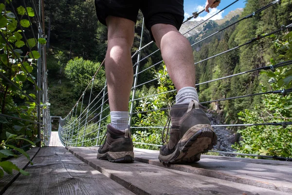 En person ung man promenader på en trä hängbro i Schweiz, vandring i en skog — Stockfoto