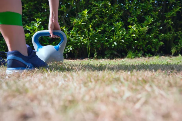 Fitness kettlebell donna cross training all'aperto su kettlebell di sollevamento grossolani e fascia di resistenza per tozzo — Foto Stock