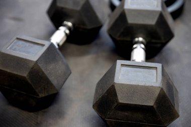 Spor salonundaki siyah lastik döşeme döşemeleri üzerinde dambıllar ya da ağırlıklar. Egzersiz için kavram