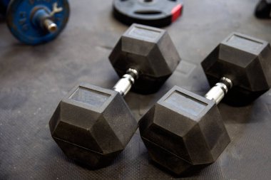 Spor salonundaki siyah lastik döşeme döşemeleri üzerinde dambıllar ya da ağırlıklar. Egzersiz için kavram