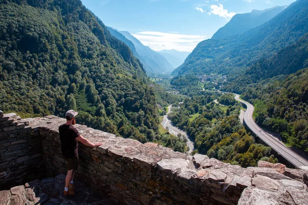 Retrato de um jovem olhando para a bela vista da montanha com estrada de carro na Suíça, Europa Alpes no verão, Viajante na estrada — Fotografia de Stock