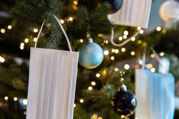 Weihnachtsbaum mit Coronavirus-Gesichtsmaske, die im Baum hängt, dekoriert mit Covid-19-Sicherheitsmaske und Weihnachtskugeln für strahlende Weihnachten — Stockfoto