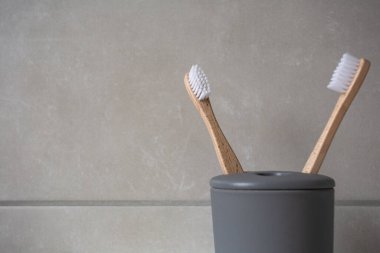 Gri tutacaklı doğal organik diş fırçaları, doğal renklerde taştan fayanslar, banyo duvarının arka plan dokusu.