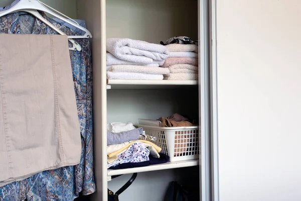 Full closet with clothes and Stack of towels in white wooden closet, organization and storage — Stock Photo, Image