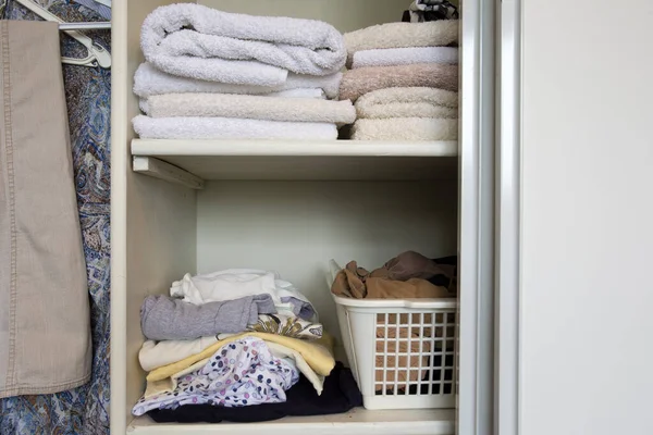 Fuldt skab med tøj og stak håndklæder i hvidt træskab, organisation og opbevaring - Stock-foto