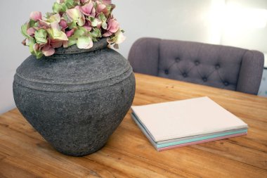 Oturma odasında boş dergi olan yemek masası, pembe çiçekli beton saksı rahat evdeki modern dekorasyon.