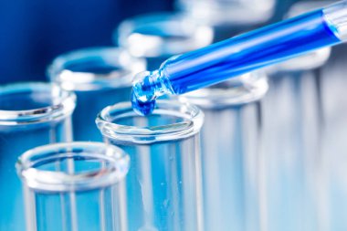 Sıvı su damlası düşmek laboratuvar test tüpü içinde mavi pipet.