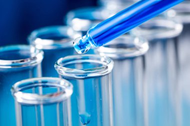 Sıvı su damlası düşmek laboratuvar test tüpü içinde mavi pipet.