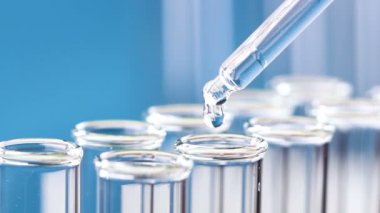 Bir pipet sıvı test tüpleri damlar. Yakın çekim.