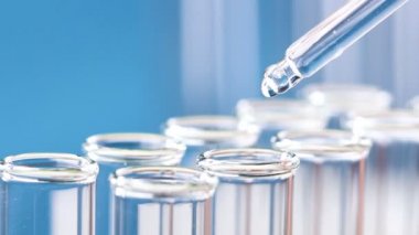 Bir pipet sıvı test tüpleri damlar. Yakın çekim.