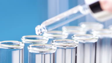 Bir pipet sıvı test tüpleri damlar. Yakın çekim.