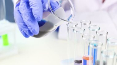 Renk sıvı cam test tüpleri içinde karışık bir bilim adamı. Yakın çekim.