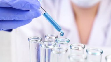 Pipet ile sıvı mavi su damla Intro cam tüp laboratuvar, yakın çekim.