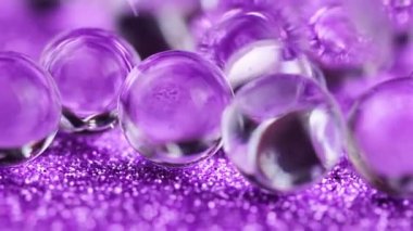 Crystal jel su topları üzerinde mor glitter doku döndürme. Makro görüntüleri kapat.